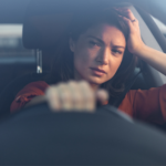 Image of a woman in the driver's seat of a car looking tired