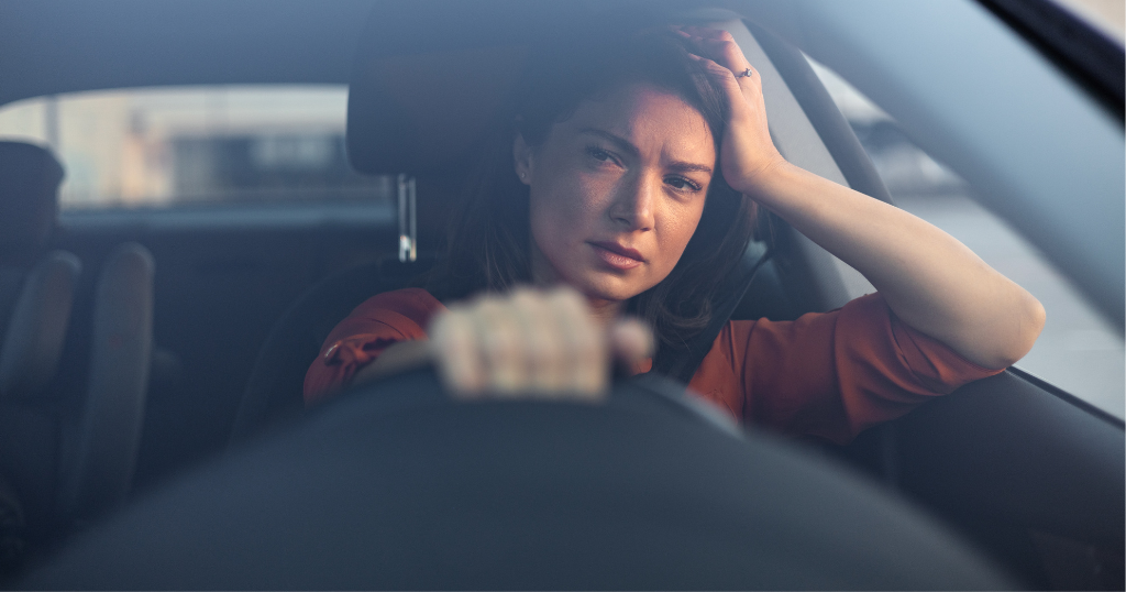 Image of a woman in the driver's seat of a car looking tired